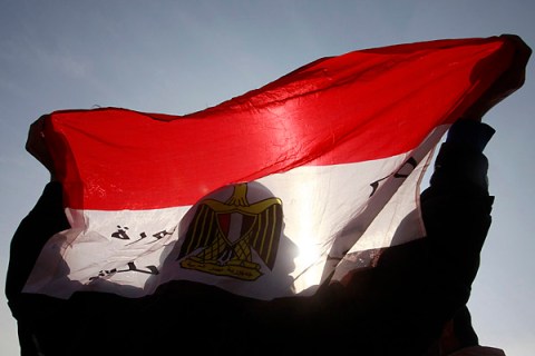 The shadow of an anti-Mubarak protester is seen as he holds an Egyptian flag in front of riot police in Cairo