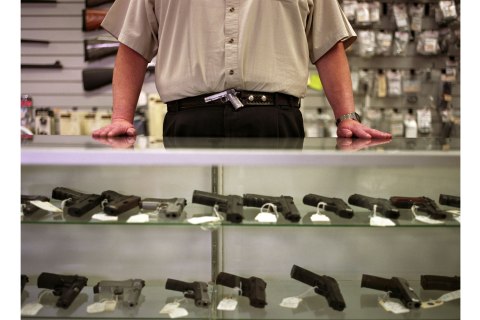 Image: Man resting hands on gun display case