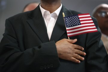 A new U.S. citizen stands while reciting the pledge of allegiance after becoming an American citizen at a naturalization ceremony held at the U.S. Citizenship and Immigration Services (USCIS), office on May 17, 2013 in New York.