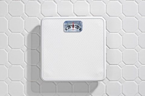 Bathroom scale on white tile floor.