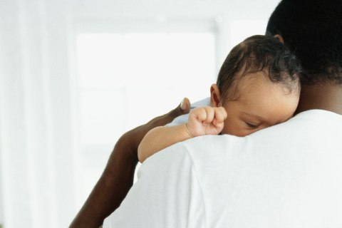 close-up of a baby asleep on father's shoulder
