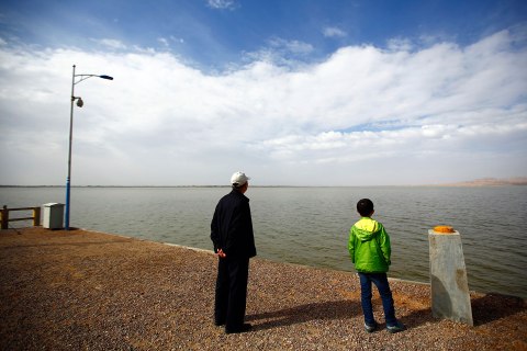 Visitors look at the Hongyashan water reservoir on the outskirts of Minqin town, Gansu province Sept. 20, 2013. 